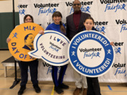 group of people holding signs in front of a Volunteer Fairfax backdrop