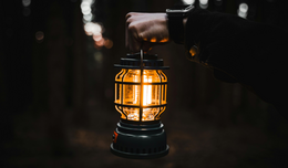 A person holds a glowing electric lantern at night.