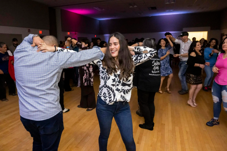 Two people dancing with a group of people dancing behind them.