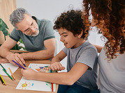 man and woman sitting with child coloring 