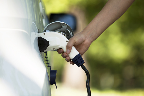Hand plugging a charging cable into an electric vehicle.