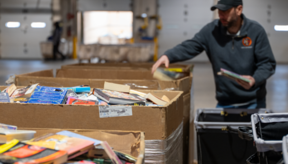 Working in a warehouse sorting withdrawn library books in large cardboard bins.