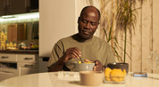 man at kitchen table with bowl of food
