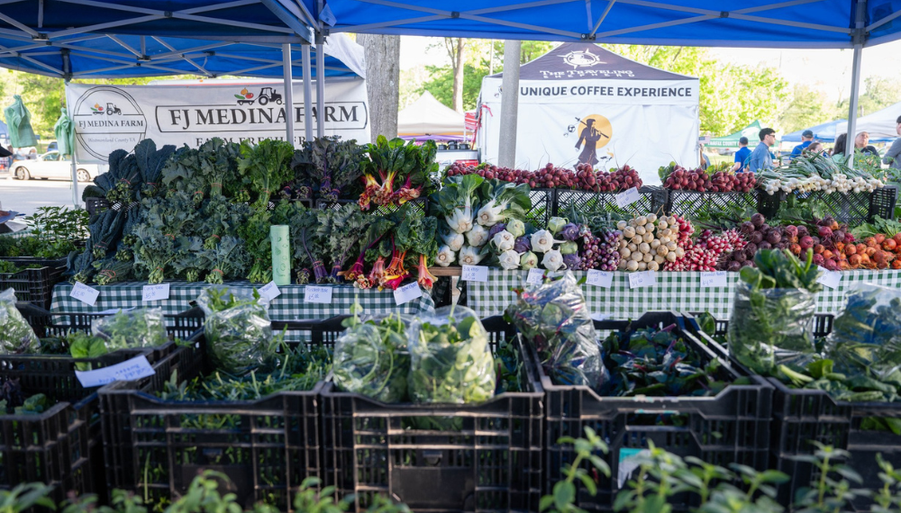 A farmers market stand filled with a variety of green leafy vegetables.
