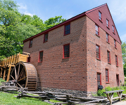 The outside of the Colvin Run Mill during summer with green trees and blue skies.