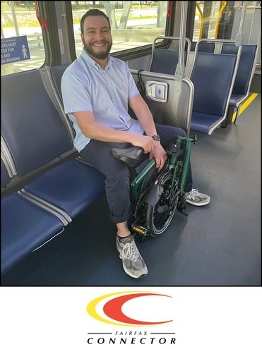 Man smiles on a Connector bus with his foldable bike in front of him.