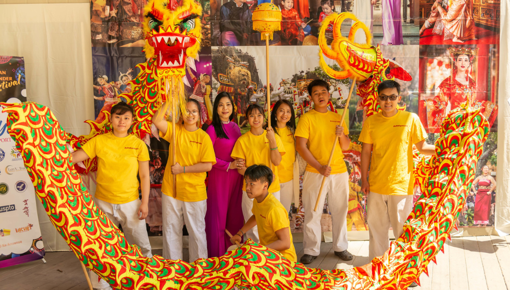 A group of people hold up a yellow dragon for a traditional dragon dance.