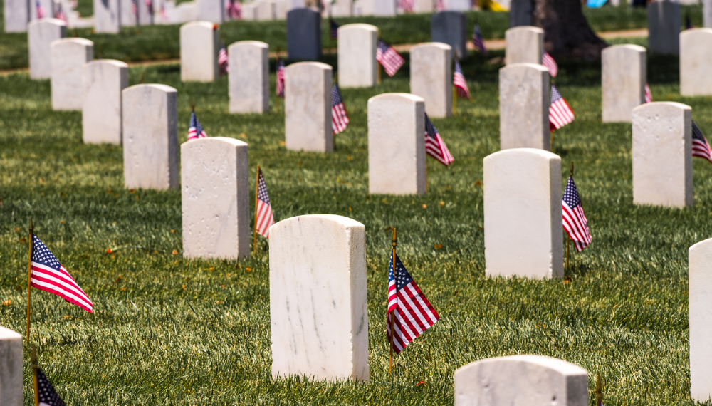 Arlington Cemetery headstones with American flags next to each headstone.