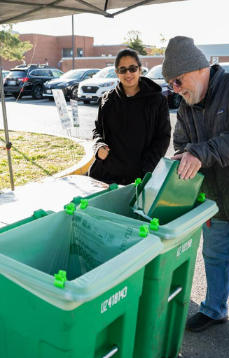 people standing at a large compost bin at a farmers market