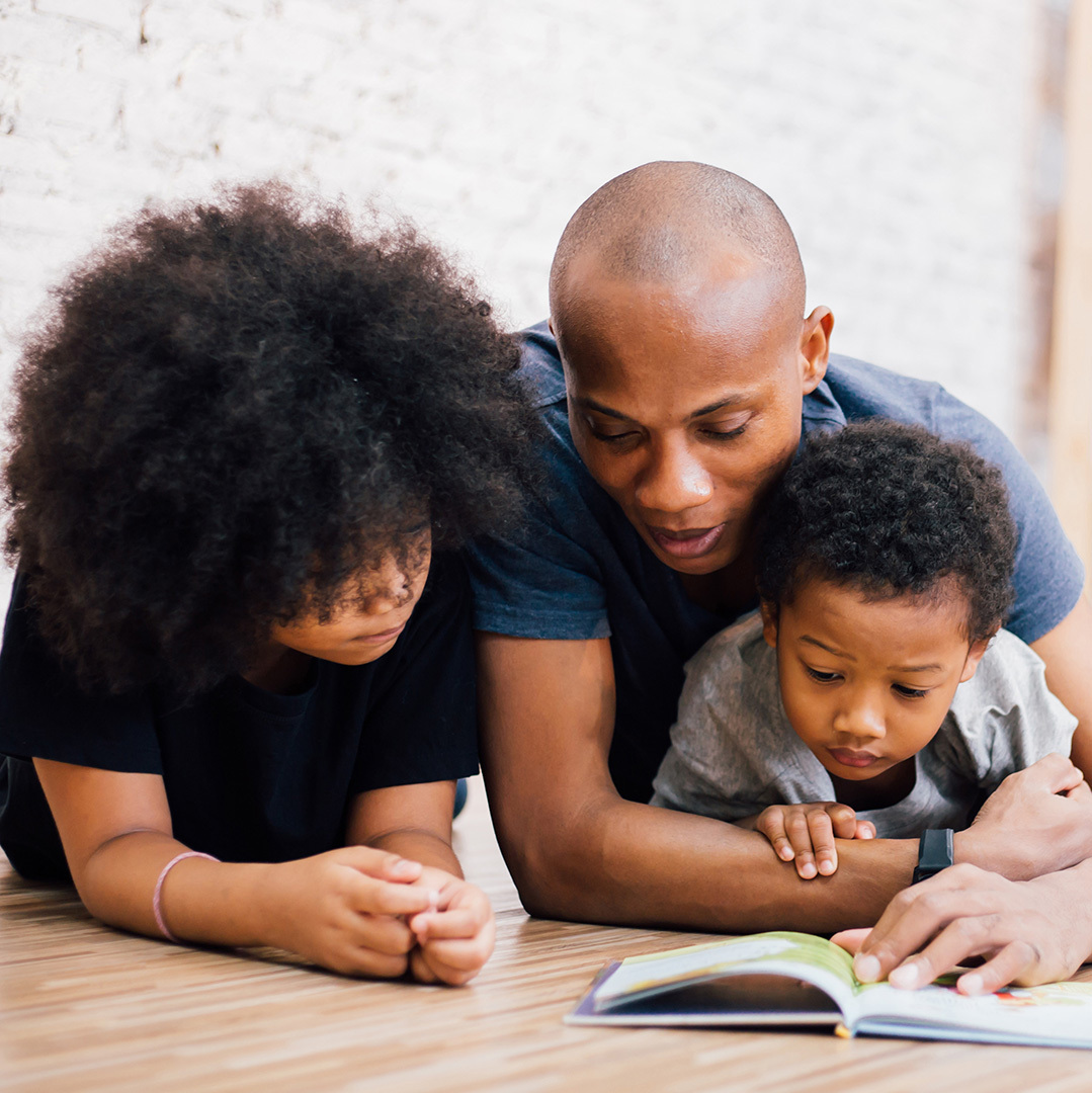 father reading to sons on floor