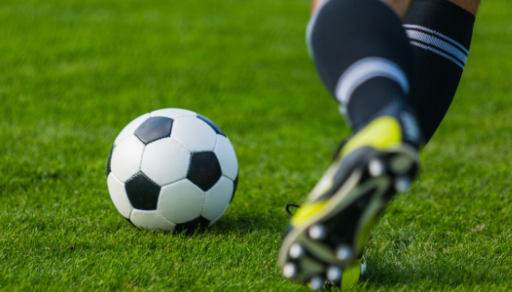 A person wearing cleats and preparing to kick a soccer ball.