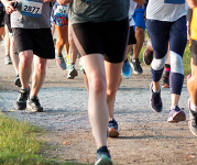 Legs of people running in athletic gear and shoes.