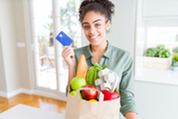 woman holding card with bag of groceries 