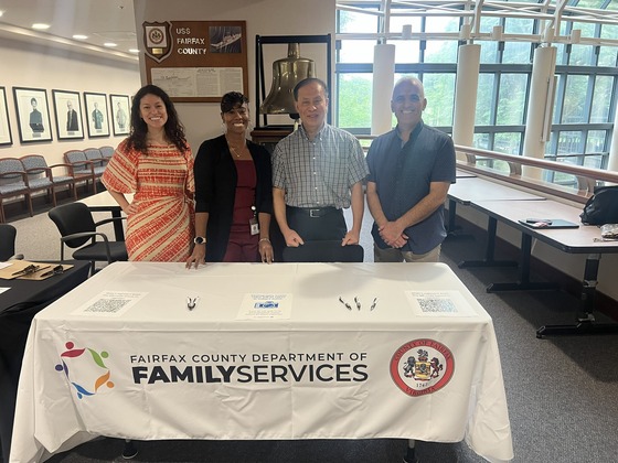 four people standing behind table