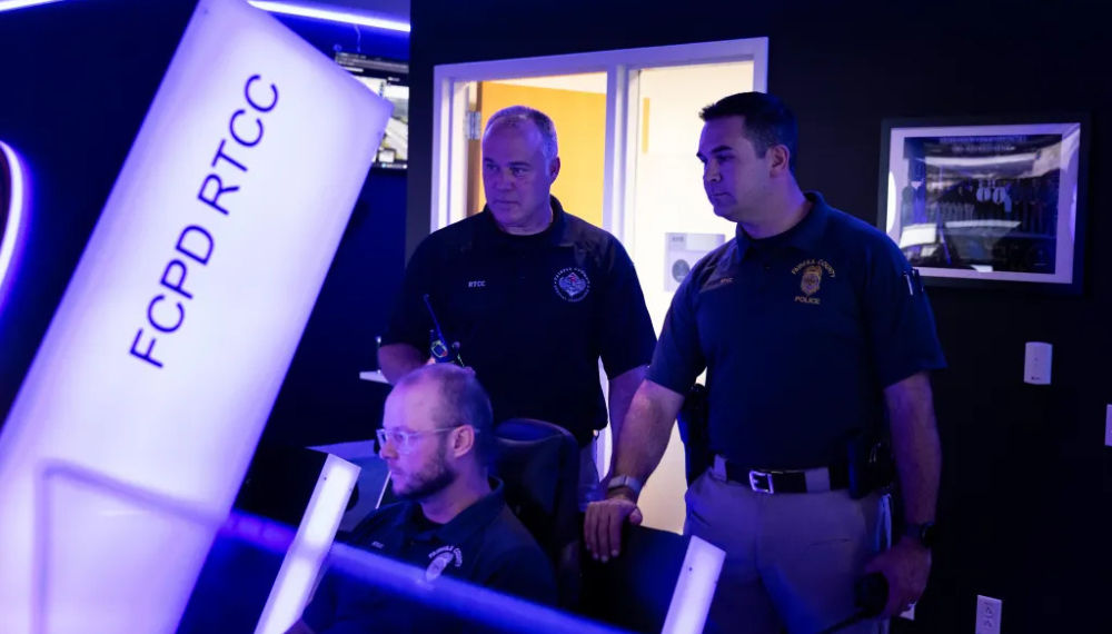 Officers standing behind an officer sitting desktop, all watching the screen. 