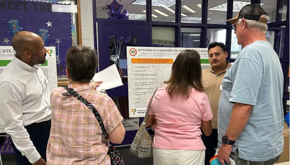 A group of people stand in front of a poster to learn about the Chantilly Library Co-Location Project.