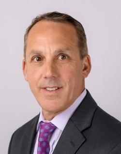 headshot of man with brown hair and grey suit