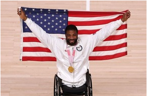 Picture of a black man in a wheelchair holding up a USA flag