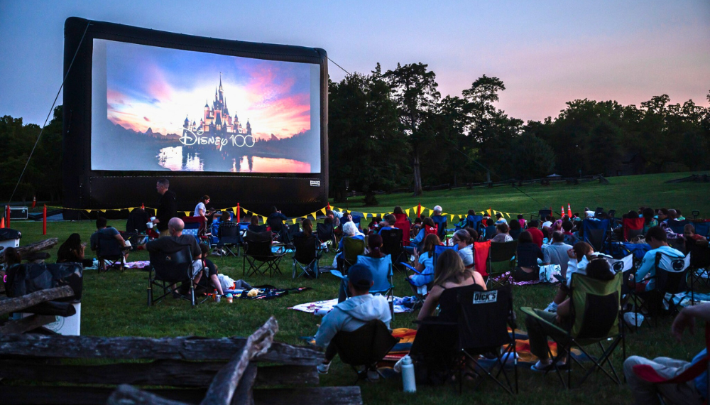 People sit in lawn chairs, watching a large inflatable screen at a previous Starlight Cinema.