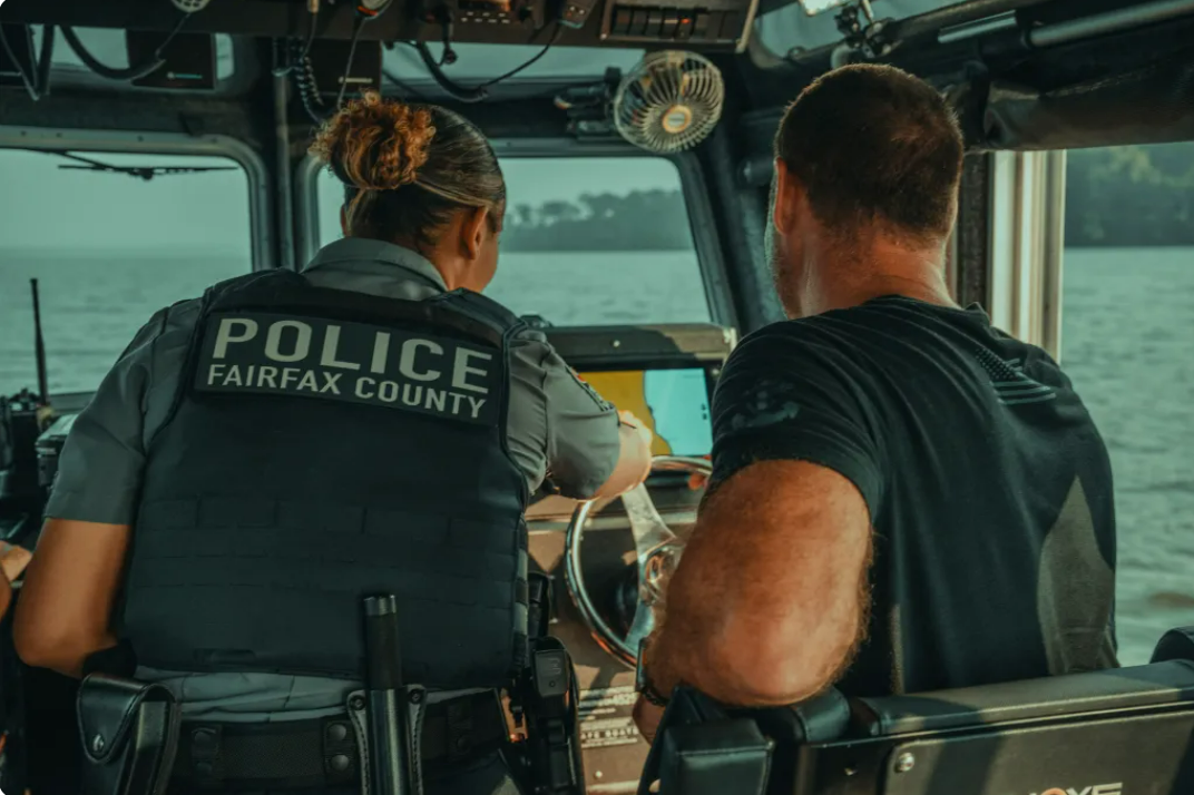 Fairfax County Police officers drive a police boat on the water.