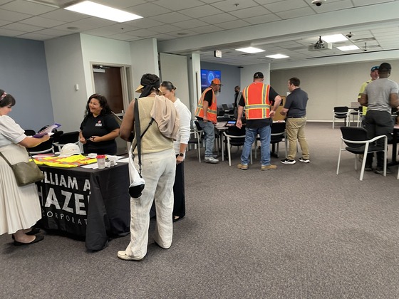 people checking in at entry table for job event and construction workers talking to each other