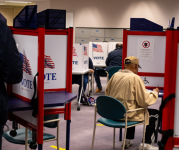 A man votes behind a divider.