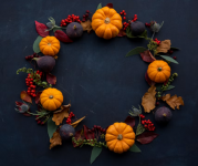 A fall wreath with mini pumpkins, figs, red berries and dried leaves.