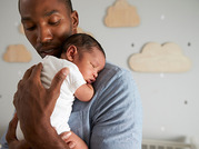 man cradling sleeping newborn