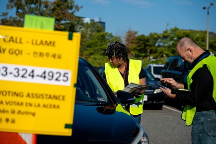 Poll workers helping a voter in their vehicle. 