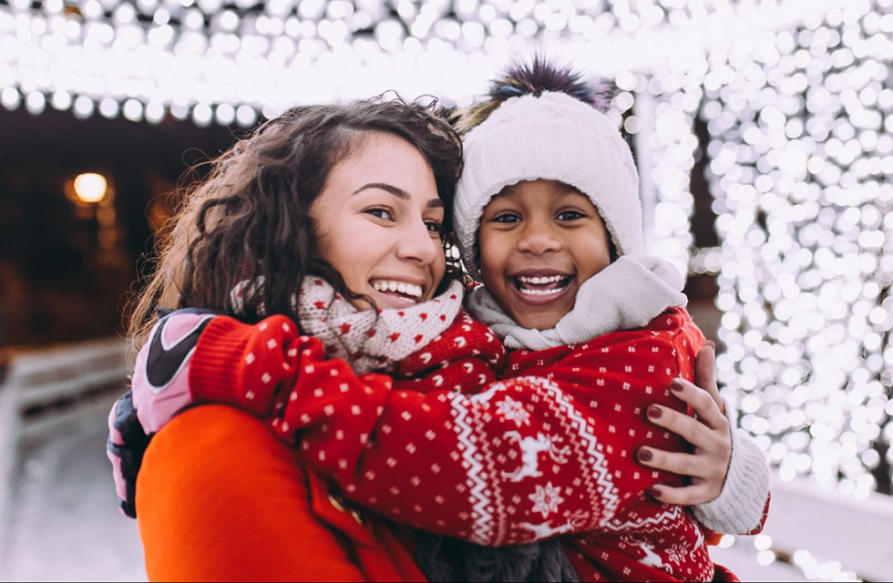 A woman holding a child looking at Christmas lights