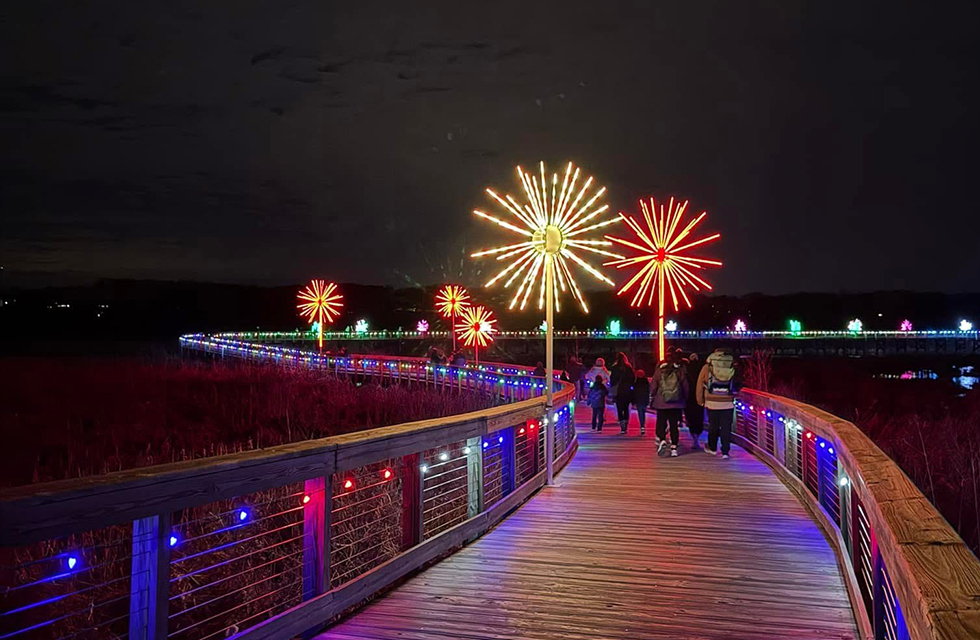 A boardwalk at night with fireworks in the sky.