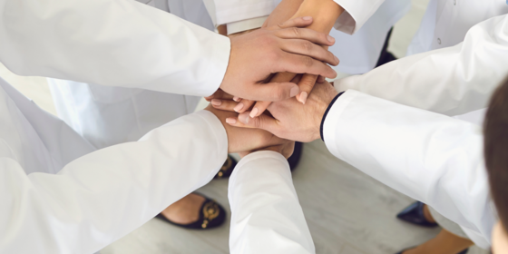 physicians with hands together in a huddle