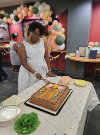 Rita cutting her chocolate cake with gifts and balloons in the background