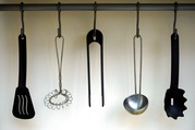 A rack of hanging kitchen cooking utensils, including plastic and metal spatula, slotted spoon, whisk and ladle.