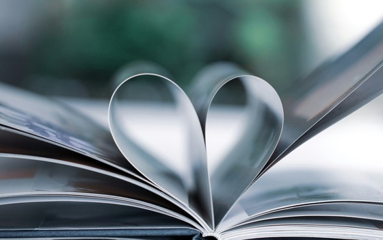 An open book with center pages folded back into the spine to appear in the shape of a heart.