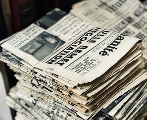 A black and white photo of a bundle of newspapers stacked on a table.