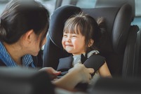 Smiling child being buckled into a car seat.
