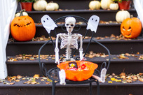 Bowl of candy on a chair in front of someone's porch. A mini skeleton sits behind the bowl.