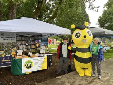 Will Peterman and Lisa Robinson pose with a honey bee mascot at the Vancouver Pollinator Festival