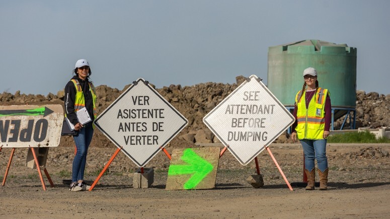 staff at yard waste drop off next standing next to sign