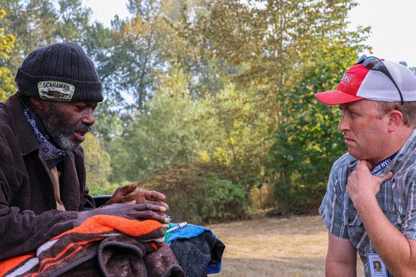 Matt Landis (right) talks with an unhoused man in a wheelchair at Brannan Park who has agreed to accept services offered.