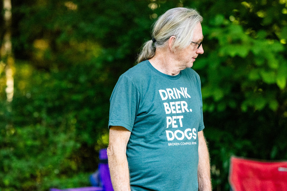 a mean wearing a shirt that says pet dogs drink beer at Hops and Crops