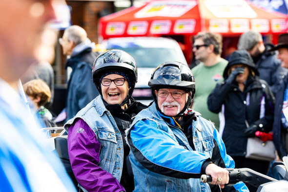 Two smiling people on a bike at Veterans Parade