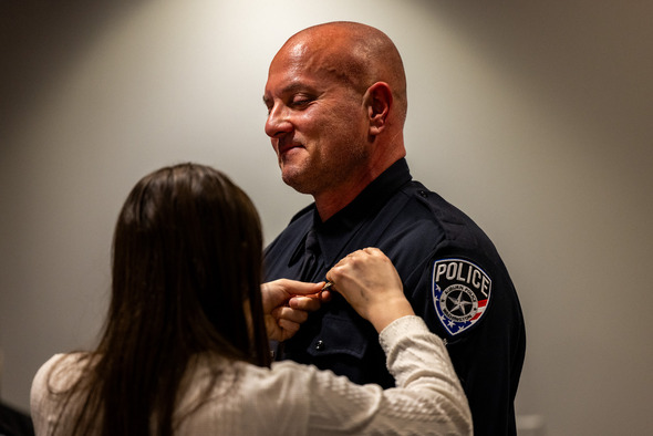 Sergeant Jason Schultz getting a pin put on his shirt by his daughter