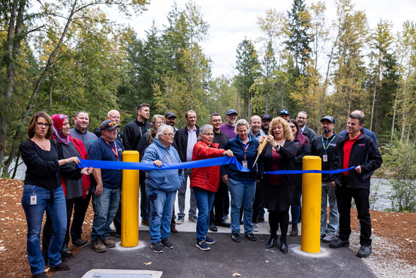 A group photo of folks ready to cut a ribbon at the bridge