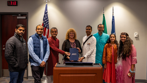 A group of people gathering behind a podium for Hindu Heritage Month