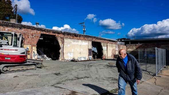 A man walking past two holes in the Auburn Ave Theater