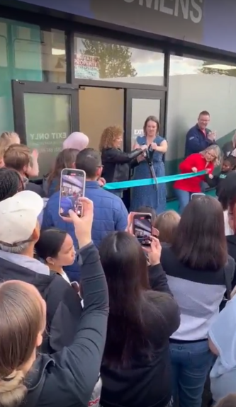 Crowd gathered around folks cutting a ribbon