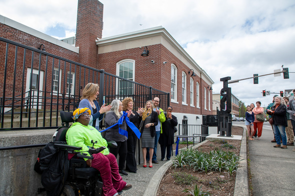 A group of people standing outside of a building cutting a ribbon 