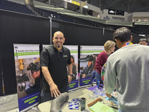 A man smiling standing behind a table at a career fair